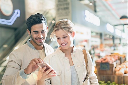 simsearch:6113-07791041,k - Smiling young couple using cell phone in grocery store market Stock Photo - Premium Royalty-Free, Code: 6124-09004891