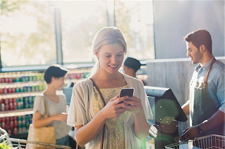 simsearch:6122-07706758,k - Young woman using cell phone in grocery store market Stock Photo - Premium Royalty-Free, Code: 6124-09004895