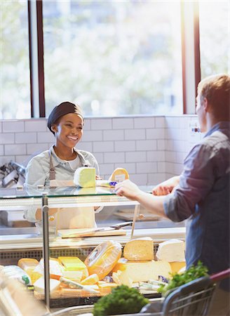 Smiling young woman helping customer at cheese counter in grocery store market Stock Photo - Premium Royalty-Free, Code: 6124-09004898