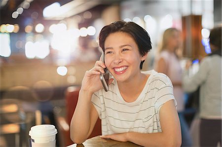 simsearch:6113-08321133,k - Smiling young woman talking on cell phone in cafe Stock Photo - Premium Royalty-Free, Code: 6124-09004813