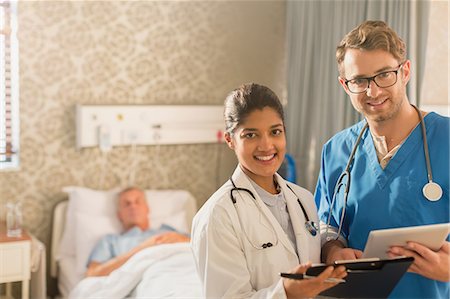 simsearch:649-09257295,k - Portrait smiling, confident doctor and nurse making rounds, using digital tablet and clipboard in hospital room Foto de stock - Royalty Free Premium, Número: 6124-09026340