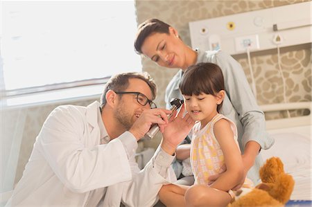 Male doctor using otoscope in ear of girl patient in hospital room Stock Photo - Premium Royalty-Free, Code: 6124-09026350