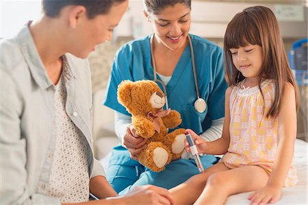 Female nurse with teddy bear watching girl patient using insulin pen in hospital room Stock Photo - Premium Royalty-Free, Code: 6124-09026375