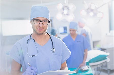 simsearch:6113-09111899,k - Portrait young male surgeon in eyeglasses with clipboard in operating room Foto de stock - Royalty Free Premium, Número: 6124-09026391