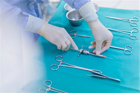 surgery tray - Surgeon in rubber gloves preparing surgical instruments on tray Stock Photo - Premium Royalty-Free, Code: 6124-09026320