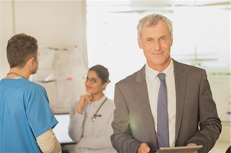 Portrait smiling, confident hospital administrator using digital tablet Foto de stock - Sin royalties Premium, Código: 6124-09026325