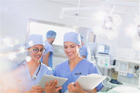 Smiling female surgeons using digital tablet and clipboard in operating room Photographie de stock - Premium Libres de Droits, Code: 6124-09026329