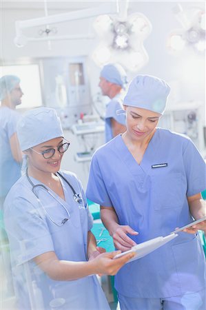 Female surgeons reviewing clipboard paperwork in operating room Stock Photo - Premium Royalty-Free, Code: 6124-09026403