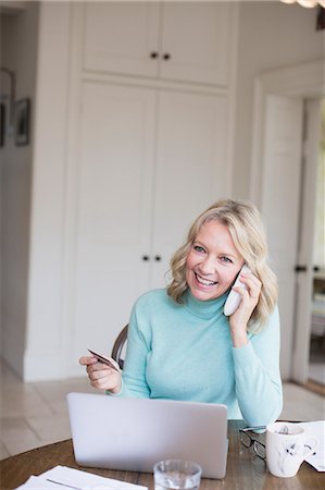 shopping phone - Smiling mature woman with credit card talking on telephone at laptop Stock Photo - Premium Royalty-Free, Code: 6124-09143711
