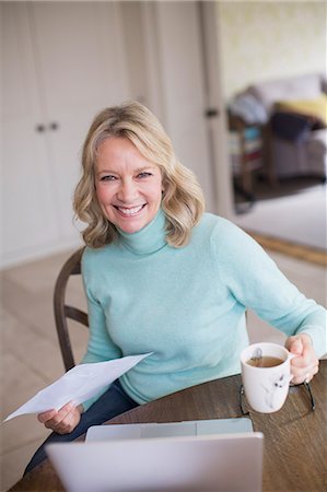 single mature woman 50s home office - Portrait smiling, confident female freelancer working at laptop and drinking tea at home Stock Photo - Premium Royalty-Free, Code: 6124-09143717