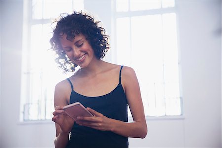 people smart phone workout not innovation not office - Smiling young female dancer texting with smart phone in dance studio Stock Photo - Premium Royalty-Free, Code: 6124-09159856