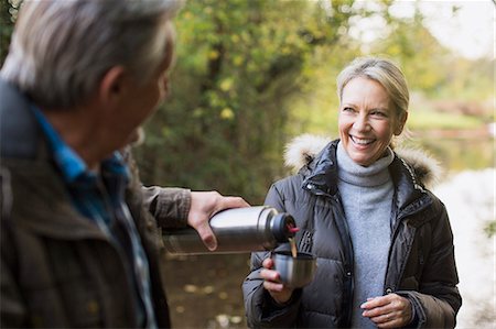 retired couple drinking coffee - Happy mature couple drinking coffee from insulated drink container in autumn park Stock Photo - Premium Royalty-Free, Code: 6124-09167255