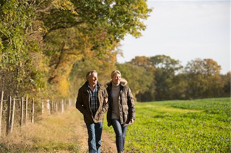 simsearch:6124-09167265,k - Mature couple walking arm in arm in sunny, rural autumn field Stock Photo - Premium Royalty-Free, Code: 6124-09167268