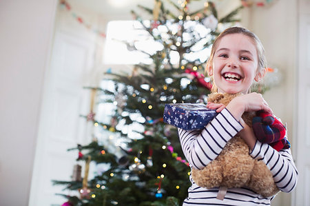 simsearch:614-06624568,k - Portrait smiling, cute girl hugging teddy bear in front of Christmas tree Stock Photo - Premium Royalty-Free, Code: 6124-09177893