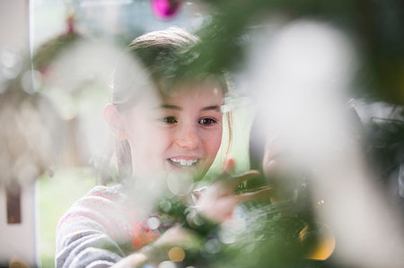 simsearch:6124-08926935,k - Smiling girl decorating Christmas tree Stock Photo - Premium Royalty-Free, Code: 6124-09177890