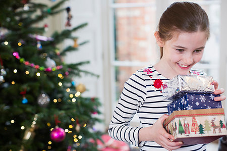simsearch:6108-05874752,k - Smiling, eager girl gathering Christmas gifts in living room Photographie de stock - Premium Libres de Droits, Code: 6124-09177895