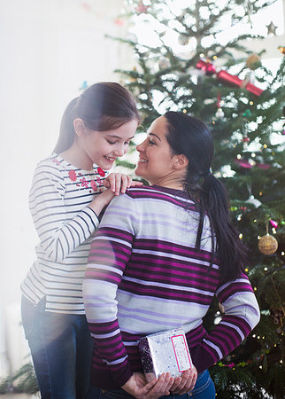 photos of christmas day living rooms - Curious girl peeking at Christmas gift behind mothers back Stock Photo - Premium Royalty-Free, Code: 6124-09177995