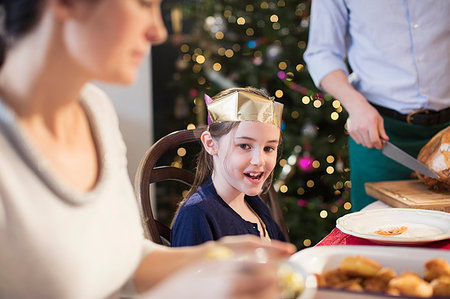 family eating dinner on special occasion - Smiling girl wearing paper crown at Christmas dinner Stock Photo - Premium Royalty-Free, Code: 6124-09177912