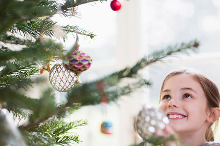 simsearch:6113-08521307,k - Smiling girl looking up at ornaments on Christmas tree Fotografie stock - Premium Royalty-Free, Codice: 6124-09177918