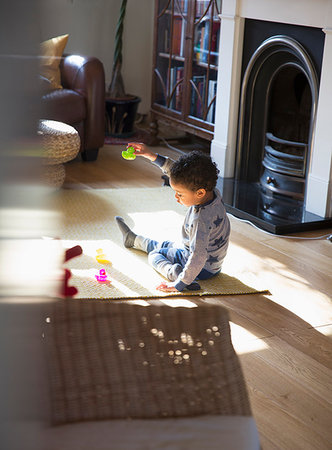 Toddler boy in pajamas playing with toys on living room floor Stock Photo - Premium Royalty-Free, Code: 6124-09178042