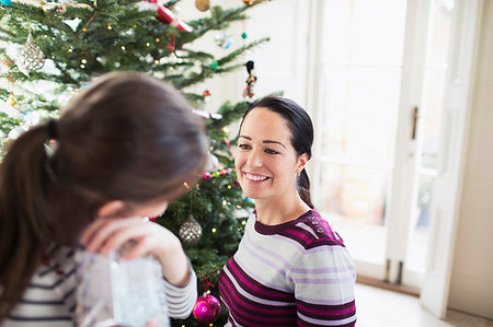 Smiling mother and daughter talking at Christmas tree Stock Photo - Premium Royalty-Free, Code: 6124-09178005