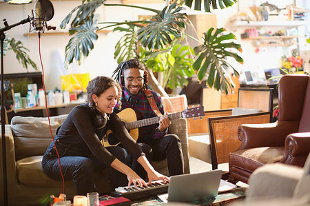 simsearch:6113-09168289,k - Young man and woman recording music, playing guitar and keyboard piano in apartment Stock Photo - Premium Royalty-Free, Code: 6124-09188550