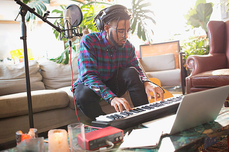 Young man recording music, playing keyboard piano in apartment Stock Photo - Premium Royalty-Free, Code: 6124-09188563