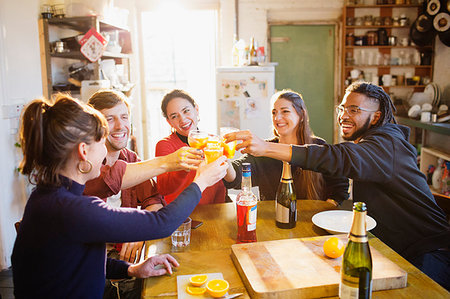 simsearch:6113-07543025,k - Happy young adult friends toasting cocktails at apartment kitchen table Stock Photo - Premium Royalty-Free, Code: 6124-09188592