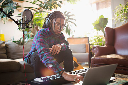 Young male musician recording music, using laptop and keyboard piano Stock Photo - Premium Royalty-Free, Code: 6124-09188500