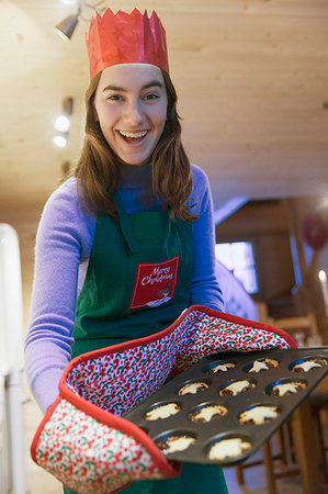 Portrait enthusiastic teenage girl in Christmas apron and paper crown baking muffins Foto de stock - Sin royalties Premium, Código: 6124-09188749