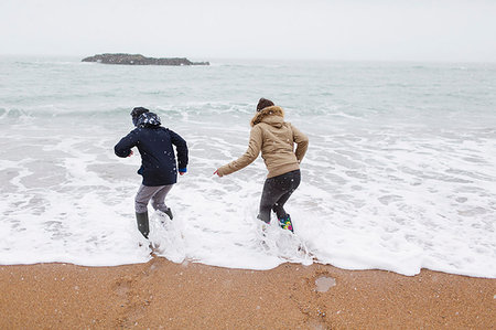 simsearch:649-08923568,k - Playful teenage brother and daughter playing in winter ocean surf Stock Photo - Premium Royalty-Free, Code: 6124-09188888