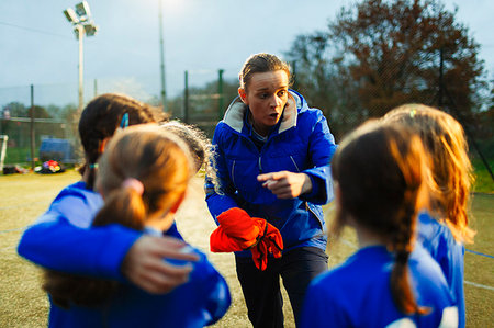 simsearch:400-06875366,k - Girls soccer team listening to coach on field at night Photographie de stock - Premium Libres de Droits, Code: 6124-09197450