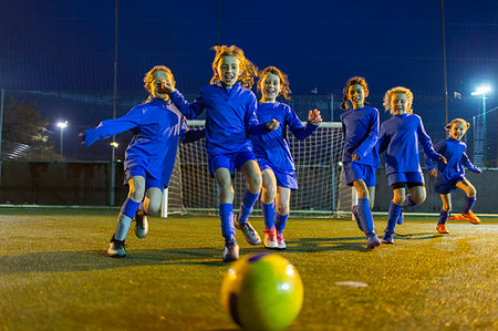 simsearch:649-06041801,k - Girls soccer team playing, running toward ball on field at night Foto de stock - Sin royalties Premium, Código: 6124-09197408