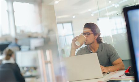 Creative businessman drinking coffee, working at laptop in office Stock Photo - Premium Royalty-Free, Code: 6124-09131061