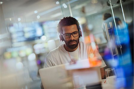 simsearch:6113-08805852,k - Focused creative businessman with headphones working at laptop in office Photographie de stock - Premium Libres de Droits, Code: 6124-09131076