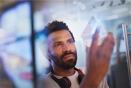 Focused, innovative male entrepreneur examining glass triangle prototype Stock Photo - Premium Royalty-Free, Code: 6124-09131010