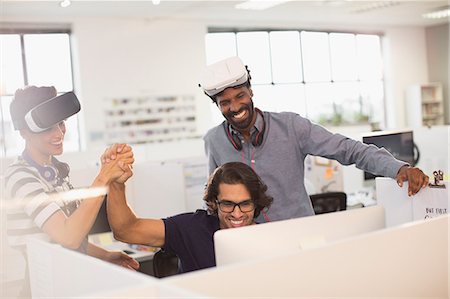 Smiling, enthusiastic computer programmers high-fiving, testing virtual reality simulator glasses Stock Photo - Premium Royalty-Free, Code: 6124-09131117