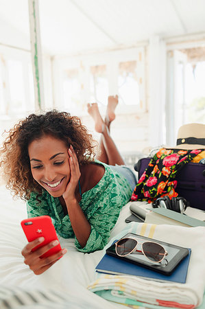 simsearch:649-08969042,k - Young woman with smart phone relaxing on bed next to suitcase and belongings Foto de stock - Sin royalties Premium, Código: 6124-09269557