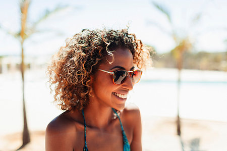 Happy young woman in sunglasses on sunny beach Stock Photo - Premium Royalty-Free, Code: 6124-09269514