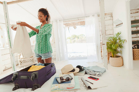 Young woman unpacking suitcase on beach hut bed Fotografie stock - Premium Royalty-Free, Codice: 6124-09269539