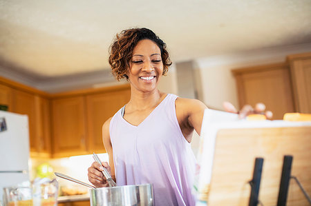 Smiling woman with cookbook cooking in kitchen Stock Photo - Premium Royalty-Free, Code: 6124-09269961