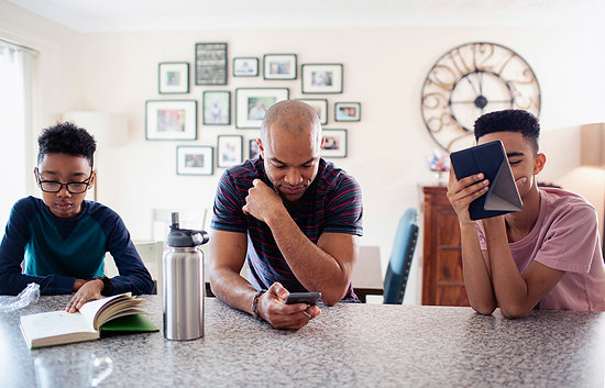 Father and sons using digital tablet, smart phone and reading book in kitchen Stock Photo - Premium Royalty-Free, Image code: 6124-09269974