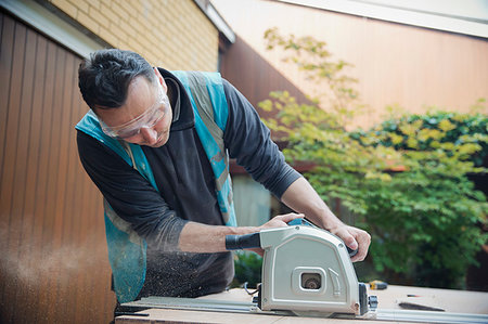 simsearch:614-05557237,k - Construction worker using table saw in driveway Photographie de stock - Premium Libres de Droits, Code: 6124-09229068