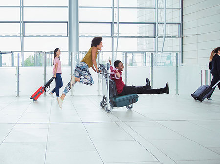 Playful couple pushing luggage cart in airport Foto de stock - Sin royalties Premium, Código: 6124-09229110