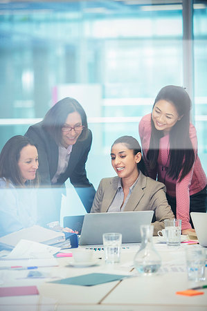 Smiling businesswomen using laptop in conference room meeting Foto de stock - Sin royalties Premium, Código: 6124-09229132