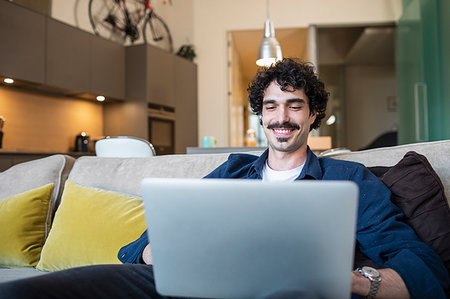 simsearch:614-09258474,k - Smiling man using laptop on apartment sofa Stockbilder - Premium RF Lizenzfrei, Bildnummer: 6124-09239461