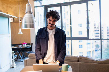 simsearch:400-03922148,k - Smiling man using laptop in apartment Foto de stock - Sin royalties Premium, Código: 6124-09239412