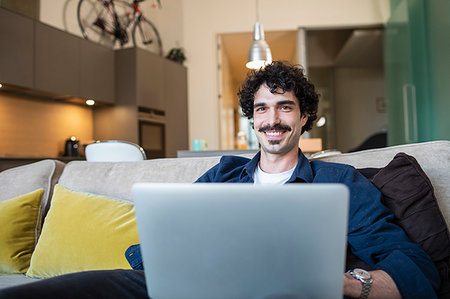 simsearch:400-04443819,k - Portrait smiling man using laptop on apartment sofa Stock Photo - Premium Royalty-Free, Code: 6124-09239427