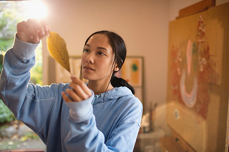 Female artist examining autumn leaf in art studio Stock Photo - Premium Royalty-Free, Code: 6124-09239605