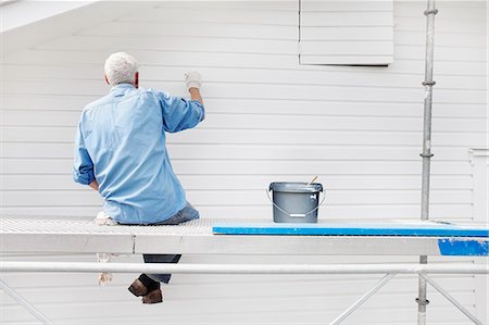 paint bucket - Sweden, Bohuslan, Rear view of senior man sitting on scaffolding and painting wall Stock Photo - Premium Royalty-Free, Code: 6126-08580619